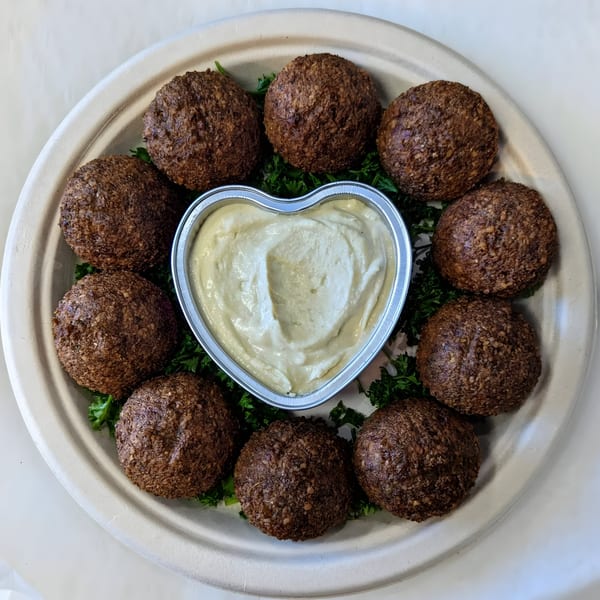Golden Chicken's falafel platter with a heart-shaped hummus dip surrounded by crispy falafel balls and parsley.