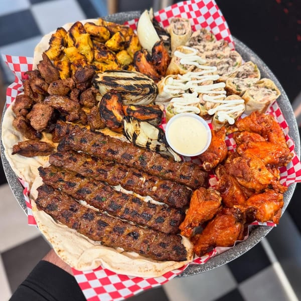 Large platter with various grilled meats, chicken wings, wraps, and grilled vegetables.
